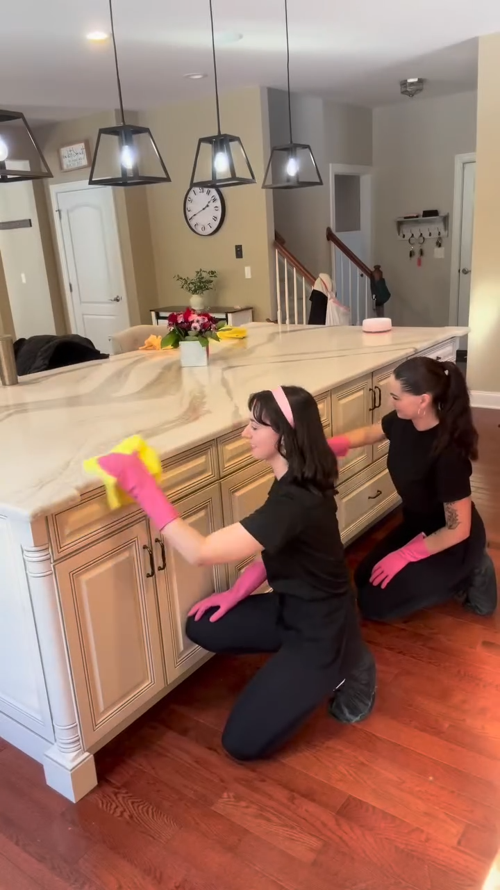 Two cleaners detailing a kitchen island